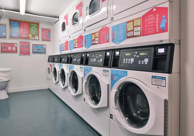 Row of stacked laundry machines with controls laundry room at iQ Bristol in Bristol Student Accommodation