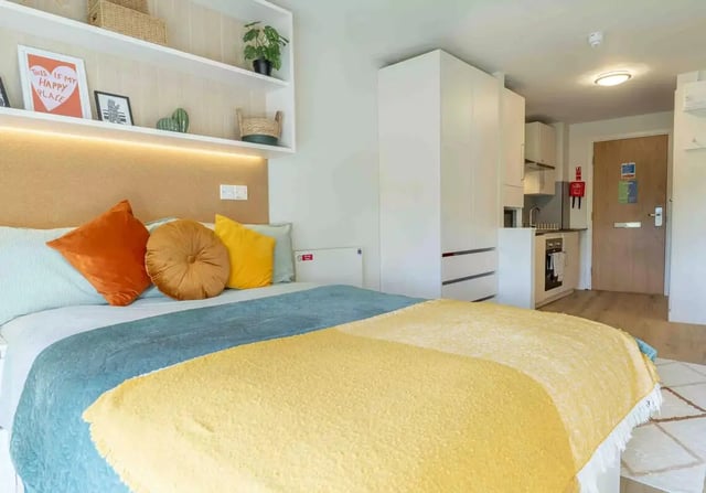 Bed with pillows wardrobe kitchen and door bedroom at iQ Bristol in Bristol Student Accommodation
