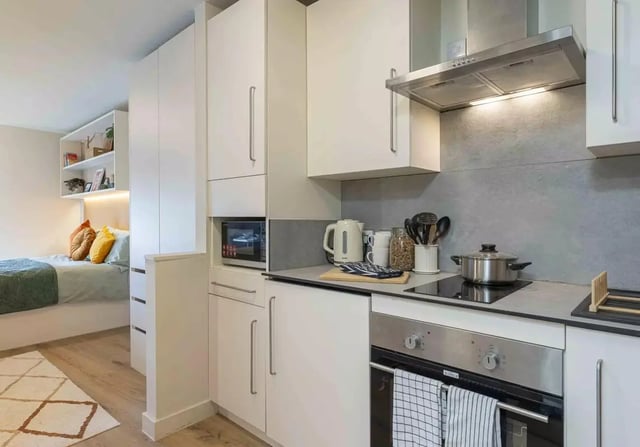 Bed with pillows and kitchen with microwave oven kitchen at iQ Bristol in Bristol Student Accommodation
