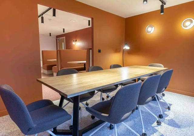 Table and chairs with booths behind communal area at iQ Leeds in Leeds Student Accommodation