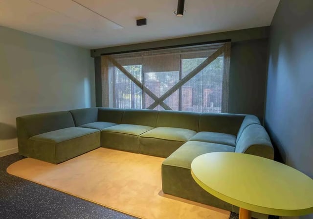 Modular green sofa with yellow oval table living room at iQ Leeds in Leeds Student Accommodation