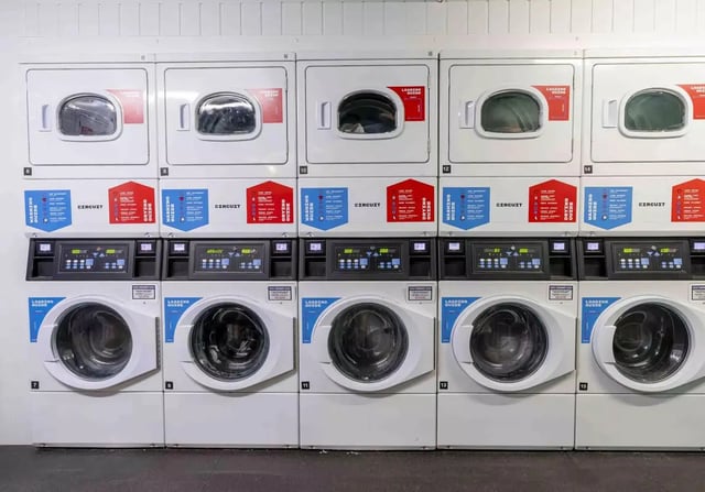Stacking white washers and dryers on wall laundry room at iQ Leeds in Leeds Student Accommodation