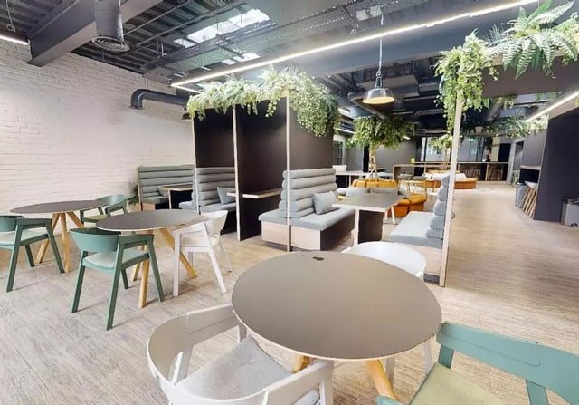 Tables chairs booths with plants communal area at iQ Shoreditch in London Student Accommodation