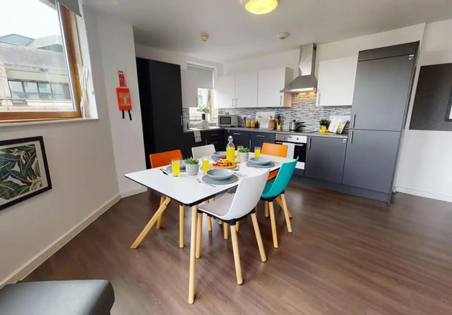 Table with chairs and kitchen area kitchen at iQ Kingston in Kingston Upon Thames Student Accommodation