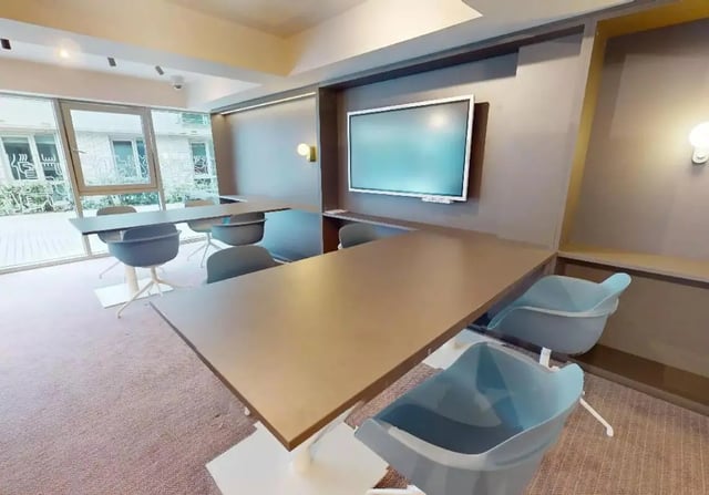 Large tables chairs and wall mounted screen communal area at iQ Hoxton in London Student Accommodation