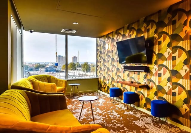 Yellow sofas blue stools patterned wallpaper living room at iQ Bloomsbury in London Student Accommodation