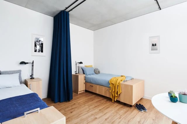 Two beds blue curtain bedside tables bedroom at Scape Uni Square in Melbourne Student Accommodation