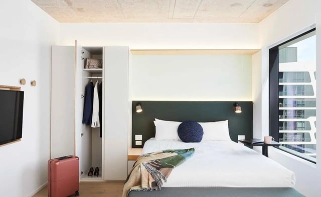 Closet bed TV suitcase and window bedroom at Scape Franklin in Melbourne Student Accommodation