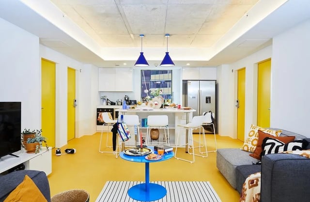Kitchen bar stools sofas and yellow doors communal living kitchen at Scape Franklin in Melbourne Student Accommodation