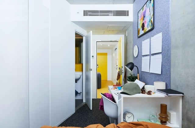 Desk with lamp artwork notes bathroom and hallway study area at Scape Franklin in Melbourne Student Accommodation