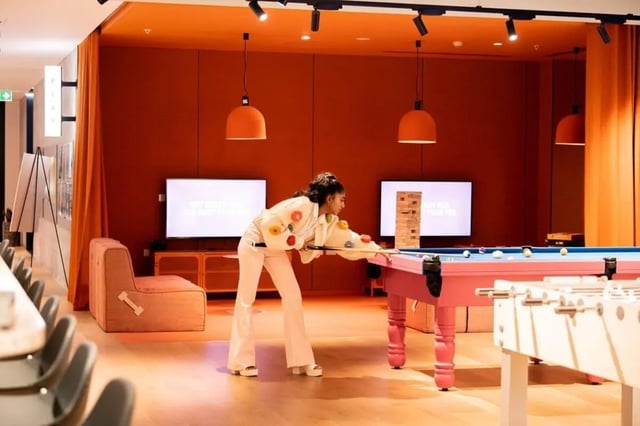 Girl plays billiards next to foosball table playing area at Scape Franklin in Melbourne Student Accommodation