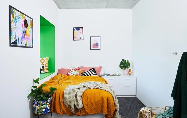 Orange bed artwork green niche and plants bedroom at Scape Franklin in Melbourne Student Accommodation