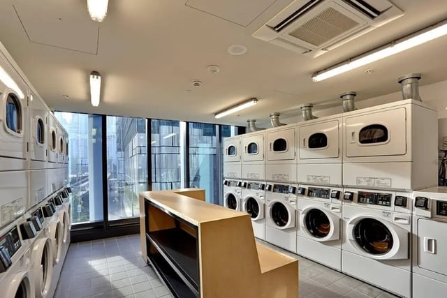 Row of washing machines and dryers with counter laundry room at Scape Darling House in Sydney Student Accommodation
