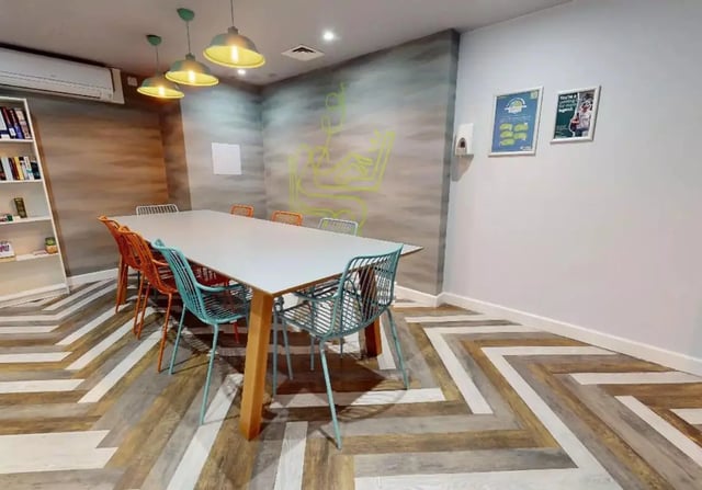 Table with chairs bookshelf and wall art study area at iQ Steel in Sheffield Student Accommodation