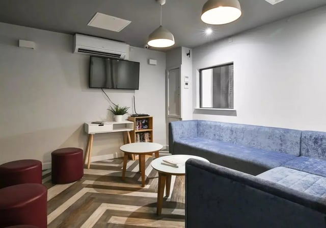 Blue sectional sofa white tables and maroon ottomans Living room at iQ Steel in Sheffield Student Accommodation