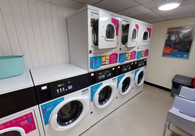 Stacking washers and dryers with control panels laundry area at iQ Brocco in Sheffield Student Accommodation