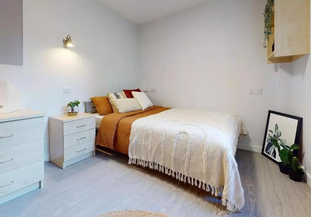 Bed with white blanket dresser and artwork bedroom at iQ Brocco in Sheffield Student Accommodation