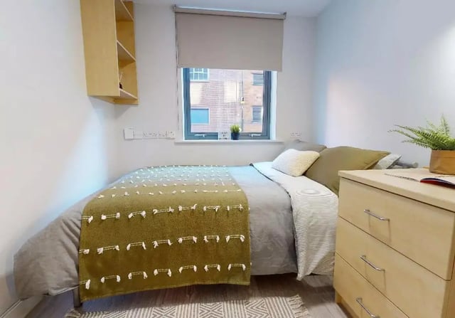Bed with green throw dresser shelf bedroom at iQ Brocco in Sheffield Student Accommodation
