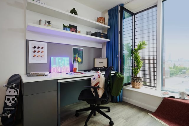 Desk chair neon sign skateboard and plant study area at Vita Student Manchester Circle Square in Manchester Student Accommodation