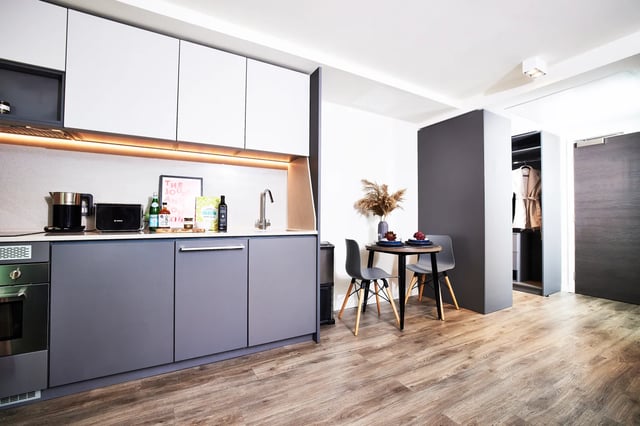 Modern grey cabinets dining table chairs open wardrobe kitchen at Vita Student Manchester Circle Square in Manchester Student Accommodation