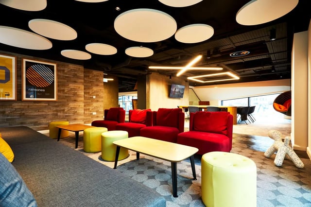 Red chairs yellow ottomans lounge living room at Vita Student Manchester Circle Square in Manchester Student Accommodation