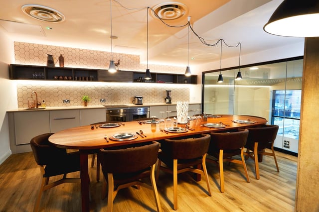 Wooden dining table set with chairs communal kitchen at Vita Student Manchester Circle Square in Manchester Student Accommodation