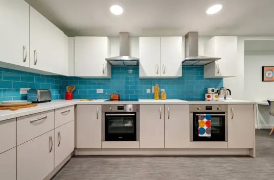 Modern kitchen with white cabinets and blue tile backsplash kitchen at Carrick View in Falmouth Student Accommodation