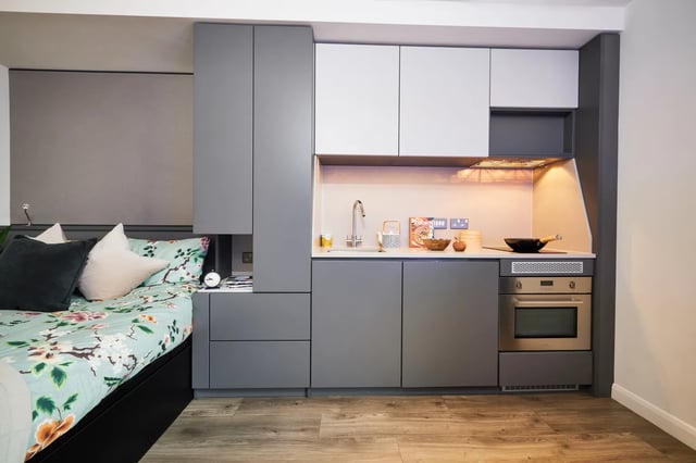 Bed with pillows sink oven grey cabinets kitchen at Vita Student Newcastle Strawberry Place in Newcastle Upon Tyne Student Accommodation