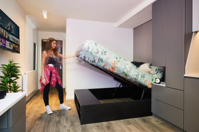 Woman lifting bed with floral duvet modern room bedroom at Vita Student Newcastle Strawberry Place in Newcastle Upon Tyne Student Accommodation