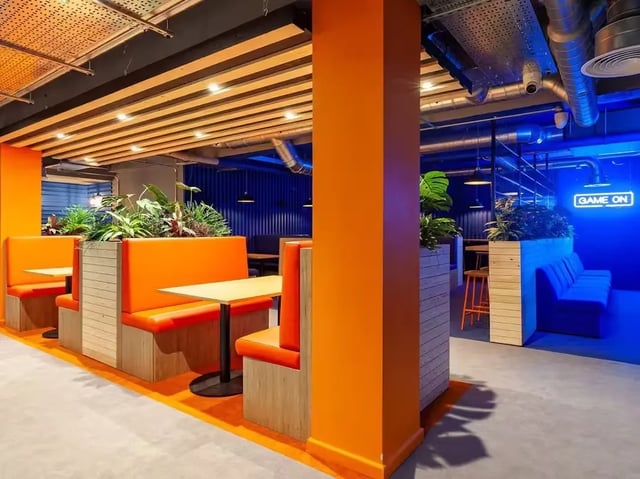 Orange booths tables plants seating area common room at The Bridge Guildford in Guildford Student Accommodation