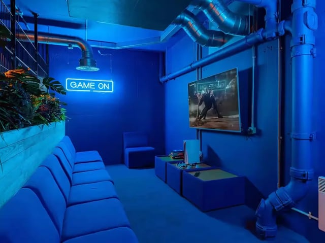 Blue sofas neon sign TV and console playing area at The Bridge Guildford in Guildford Student Accommodation