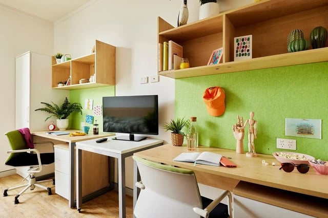 Two desks chairs monitors plants shelves accessories study area at Scape Cleveland in Sydney Student Accommodation