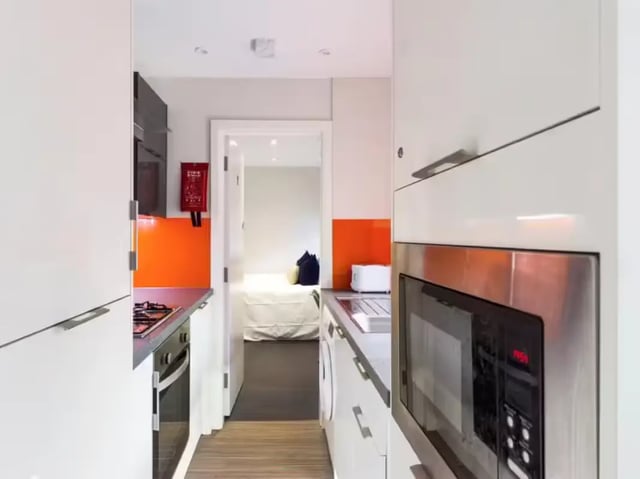 Modern kitchen with microwave stove and doorway to bedroom kitchen at 16 Queen Anne Street in Stoke-On-Trent Student Accommodation