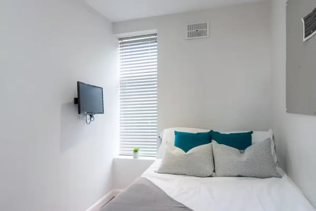 Bed with teal and gray pillows mounted TV bedroom at 80 Beresford Street in Stoke-On-Trent Student Accommodation