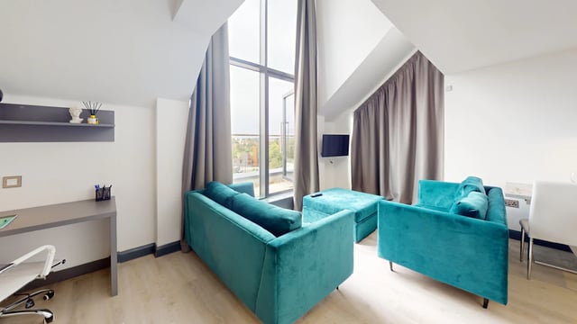 Turquoise sofas ottoman desk television living room at The Residence in Coventry Student Accommodation