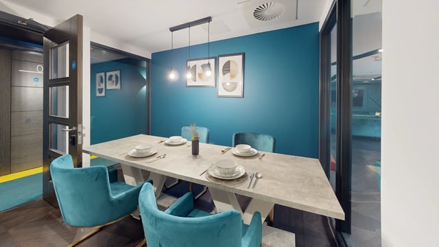 Dining table with blue chairs and artwork Dining area at The Residence in Coventry Student Accommodation