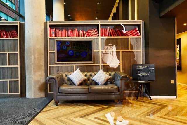 Brown leather sofa with pillows and bookshelf living room at Vita Student Manchester First Street in Manchester Student Accommodation