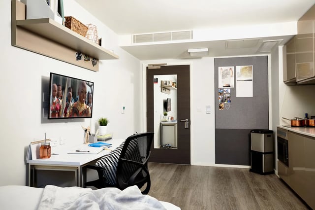 Desk TV chair and kitchen area studio at Vita Student Manchester First Street in Manchester Student Accommodation