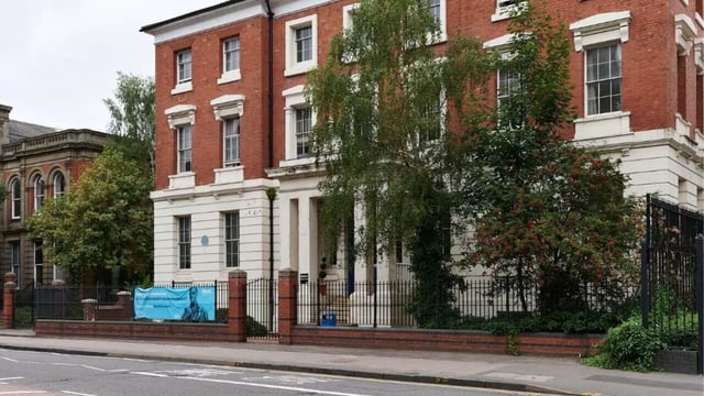 Red brick building with black fence and trees exterior at Queen's Hospital Close in Birmingham Student Accommodation