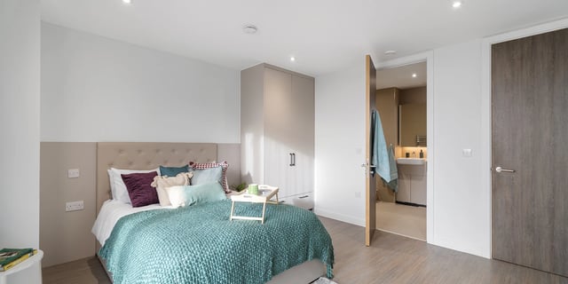 Bed with teal blanket opening to bathroom bedroom at Canvas Coventry City Club in Coventry Student Accommodation