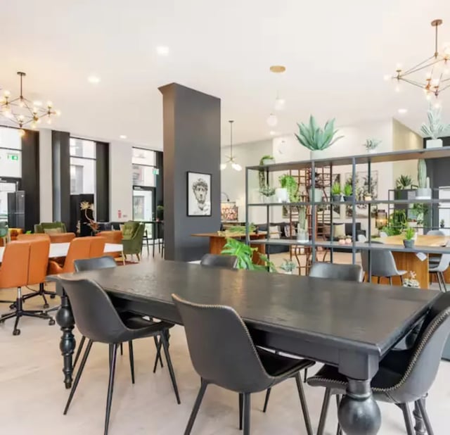 Large dark table with chairs plants living area at Zinc Quarter in Bristol Student Accommodation
