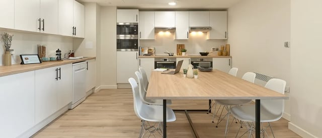 White cabinets dishwasher table with laptops and chairs kitchen at Christchurch Road in Bournemouth Student Accommodation