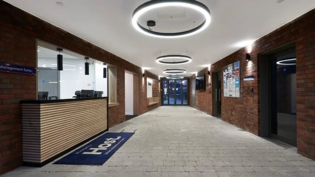 Reception desk with circular lights and brick walls lobby at 41 Castle Street in Leicester Student Accommodation