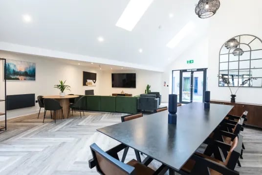 Long dining table lounge sofas and round table living room at Riverside House - Manchester in Salford Student Accommodation