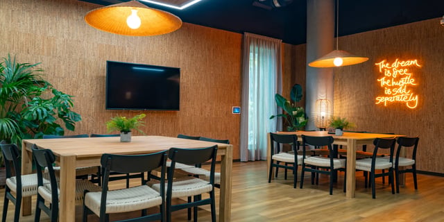 Dining tables chairs plants television and neon sign communal area at Canvas Manchester in Manchester Student Accommodation