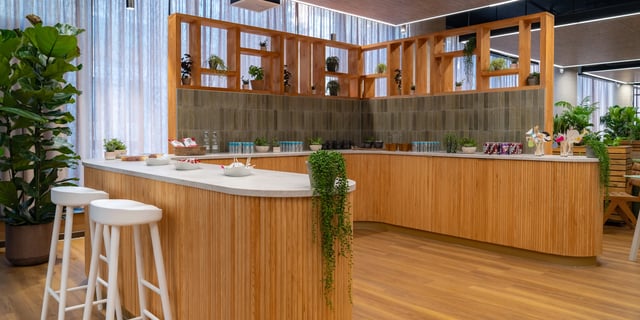 Wooden bar with stools and plants communal area at Canvas Manchester in Manchester Student Accommodation