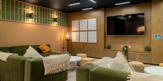 Green sofas coffee tables poufs and TV living room at Canvas Manchester in Manchester Student Accommodation