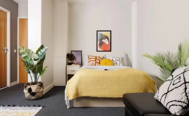 Bed with yellow blanket bedside table plants bedroom at Riverside Point in Nottingham Student Accommodation