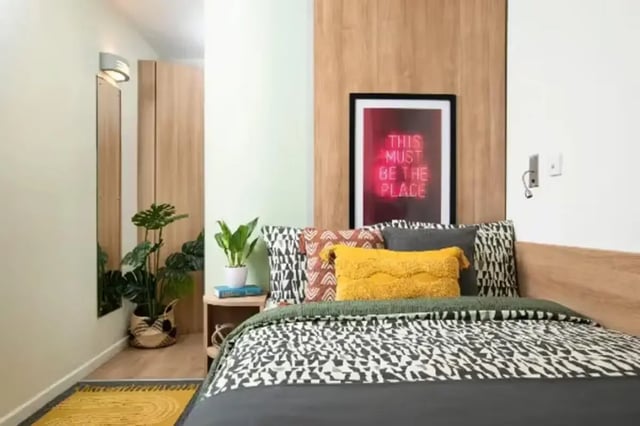Bed with patterned bedding neon art bedside plants bedroom at Emily Bowes Court in London Student Accommodation