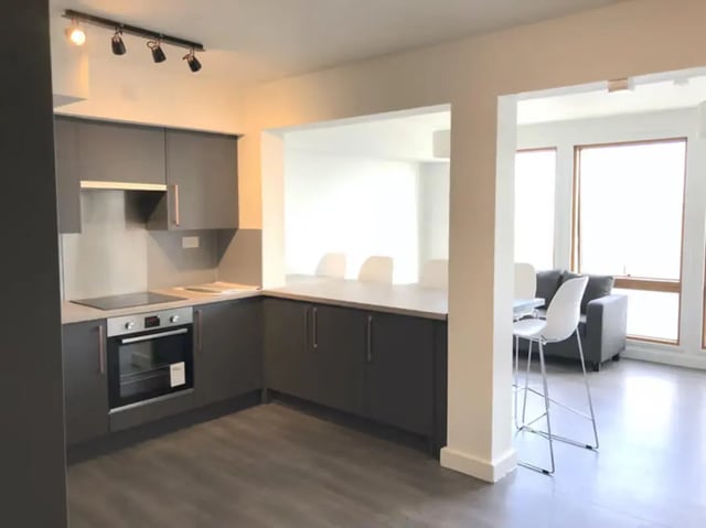 Modern kitchen with oven bar stools and sofa living room at Charles Morton Court in London Student Accommodation